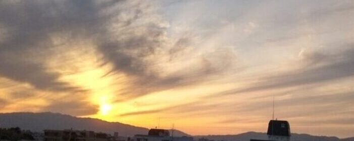 山の後ろに沈みゆく夕日の写真